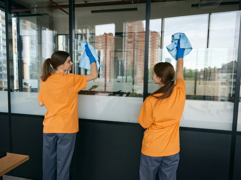 Cleaning company employees washing windows in a coworking space