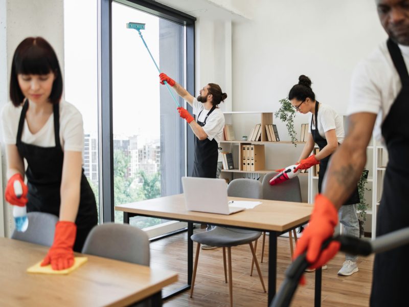 People of cleaning service cleans tables, floor, and panoramic windows.